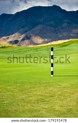 A black and white distance marker on a golf fairway