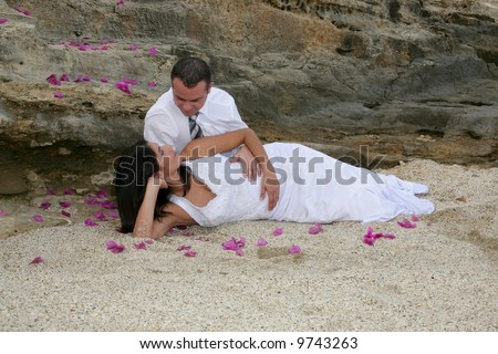 Just Married - bride in groom\'s arms on the beach and bed of flowers