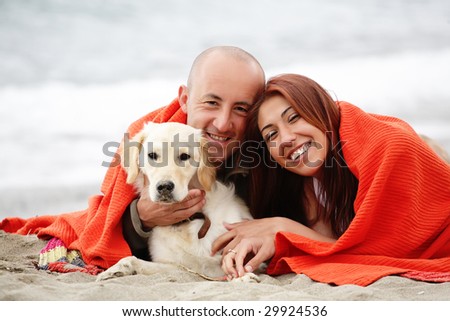 attractive romantic couple with a dog having fun on the beach