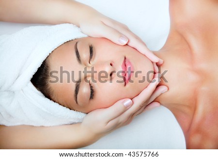 Beautiful young woman receiving facial massage.