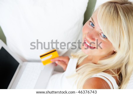 Online shopping - young smiling woman sitting with laptop computer and credit card in her hand.