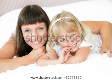 Mother and daughter posing happily in bed. Shallow DoF. Focus on daughter.