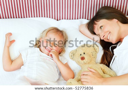 Bed Time - mother and daughter lying in bed and smiling happily.