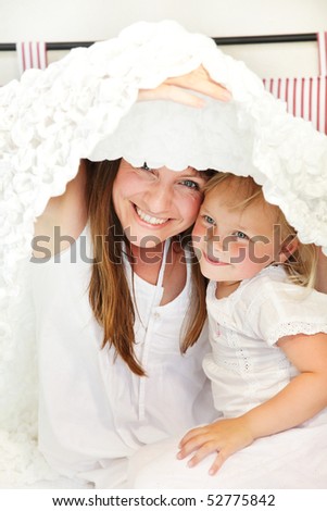 Mother and daughter playing peek-a-boo in bed. Shallow DoF.  Focus on mother.