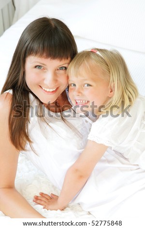 Mother and daughter posing happily in bed. Shallow DoF. Focus on mother.