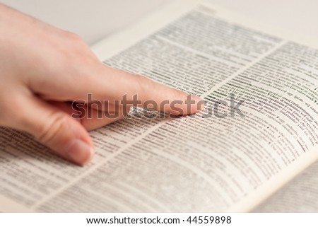 Finger of a female hand pointing a term on a book
