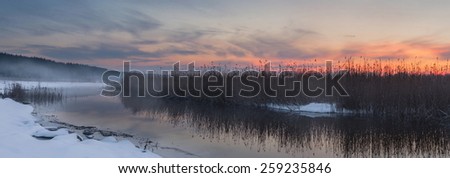 Panorama the river in the winter at sunset with fog. A bright sunset of the sun on the river