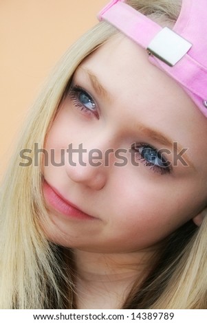 Portrait of a nice attractrive dreaming young girl teenager with pink base-cap and long blond hair