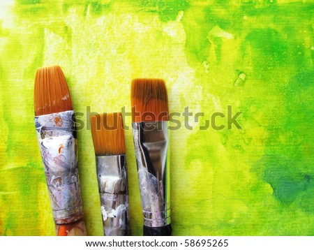 Artists paint brushes in studio in front of abstract background