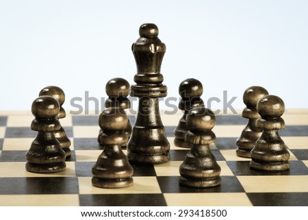 Team symbol with wooden chess pawns and chess queen. Leadership concept.