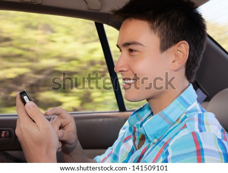 Young man in the car using his mobile phone