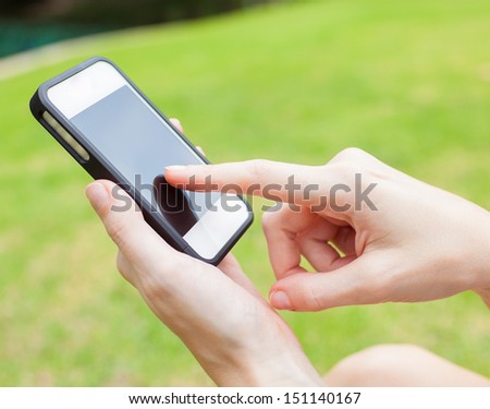 Female using mobile smart phone outdoor in park.