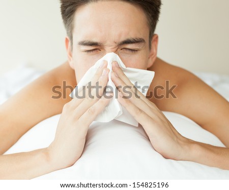 Sick man. Flu. Sneezing into tissue. Man caught cold.