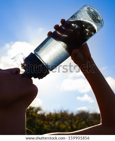 Silhouette of young woman drinking water