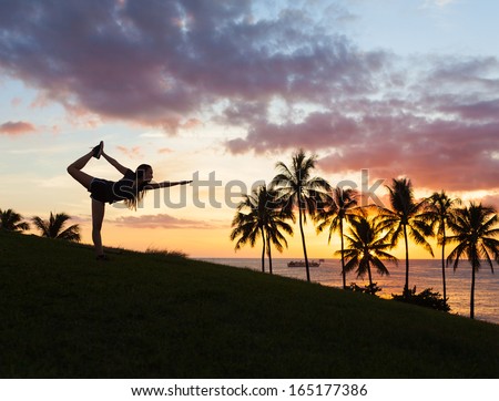 Female silhouette practicing yoga during sunset