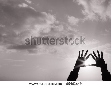 Silhouette of hands holding up the sun