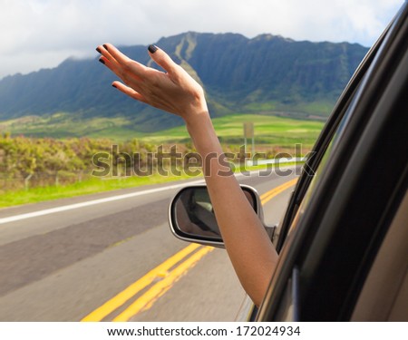Woman driver feeling the wind through her hands while driving in the country side.(freedom concept)