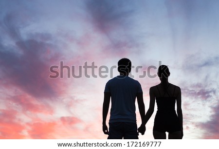 Silhouette Of Young Couple Holding Hands Looking At The Sunset