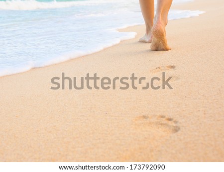 Woman walking on sand beach leaving footprint in the sand. Beach travel.