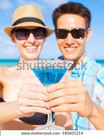 Man and woman enjoying cocktail drink on the beach in Hawaii.
