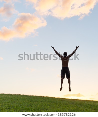 Silhouette of young happy man jumping in the park. Enjoyment. Freedom concept.
