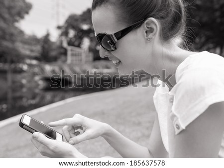 Pretty young girl using cellphone smart phone (black and white portrait).