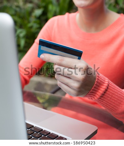 Woman holding credit card and using computer for online shopping.