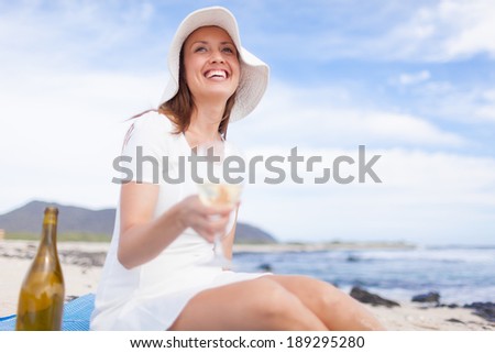 Beautiful smiling woman having glass of wine on the beach in Hawaii, USA.