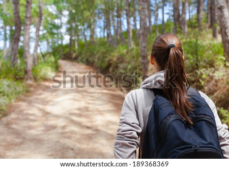 Hiker woman with backpack walking through a forest.