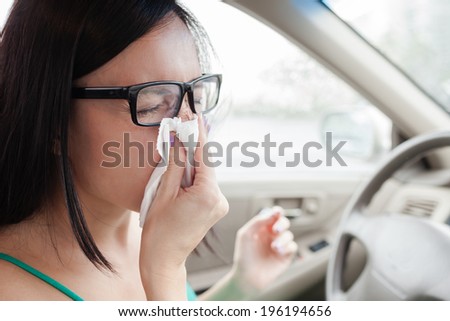 Woman driver sneezing in the car. Sick woman driver.