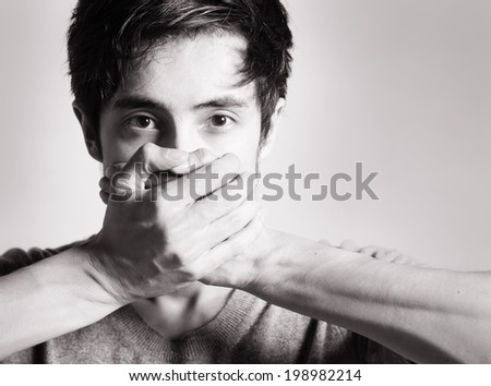 Speak no evil concept - face of asian man covering his mouth.