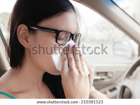 Sick woman driver. Woman driver sneezing in the car.