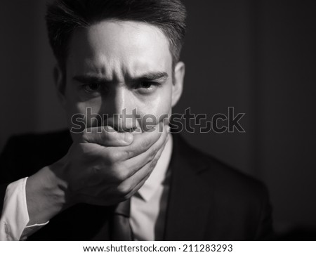 Business man covering his mouth - speak no evil concept.
