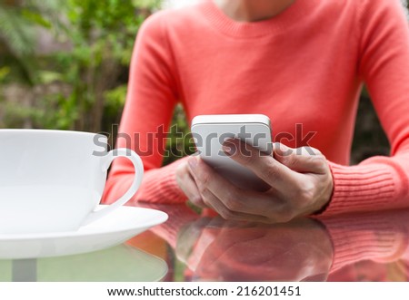 Woman texting on smart phone mobile at an outdoor coffee shop