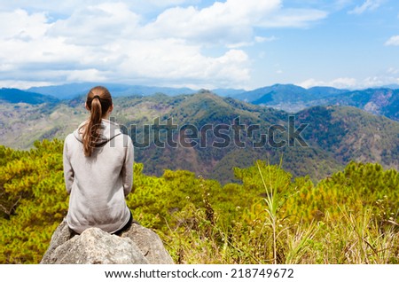 Tourist woman relaxing on rock and enjoying beautiful landscape