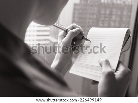 Woman writing a letter, notes. Close up view of her hand and the document