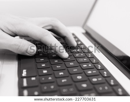 Man\'s hand typing on laptop keyboard
