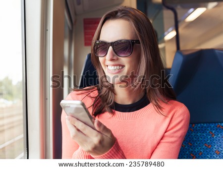 Beautiful young woman using mobile smart phone on train