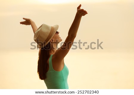 Woman with hands raised in the sunset.