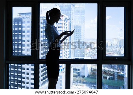 Business woman using her phone in a office setting.