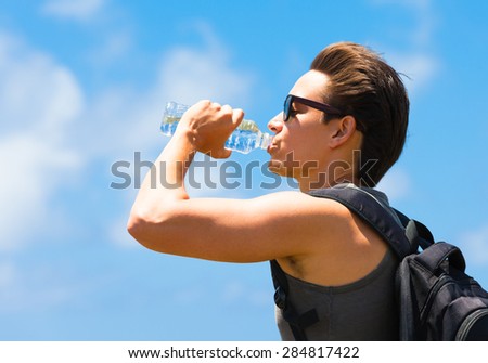Fit male drinking water outdoors.