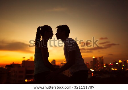 Couple kissing on a city roof top.