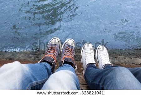 Couples feet relaxing on a bridge.
