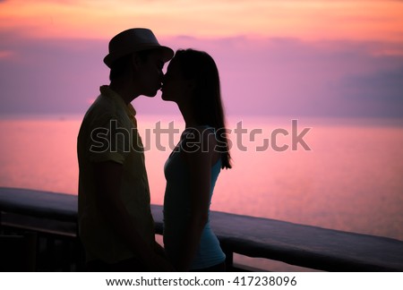 Romantic couple kissing at sunset.