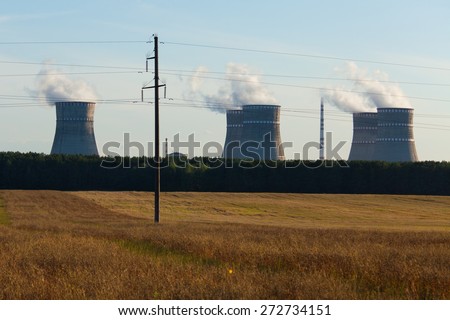 Six chimneys with white smoke of the working nuclear plant near yellow field on a summer evening - August 24, 2013, circa Rivne region, Ukraine