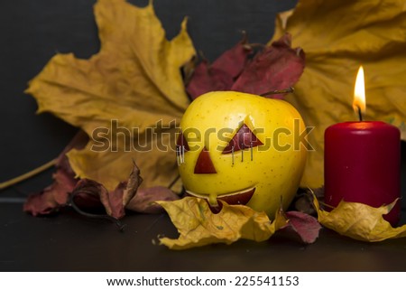 apples with faces for Halloween surrounded by autumn leaves and candles