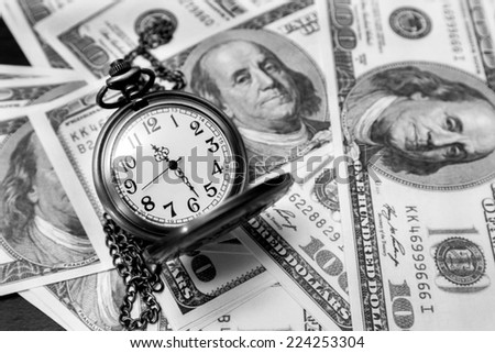 Pocket watch and dollar bills in black and white
