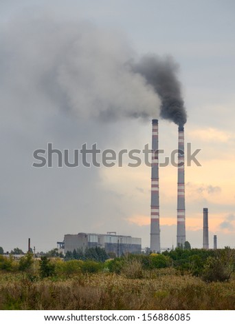 smokestack polluting the environment in Donetsk Ukraine. gray smoke against the sunset and the cloudy sky. vertical image.