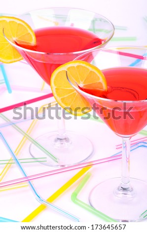 two glasses with red cocktail and yellow lemon slices on a light background. Cocktail tubes on background.  view from above. vertical