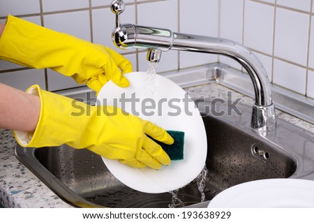 Woman\'s hands in the gloves wash plate horizontal closeup